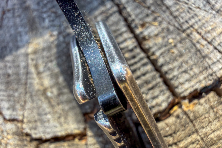 Close-up of the Coast Contra frame lock and blade spine showing sand packed into the pivot area.