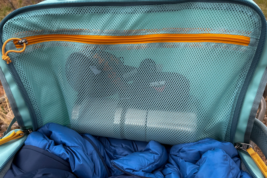 Interior of the Cotopaxi Allpa Getaway 55L showing a large mesh lid pocket above packed clothing.