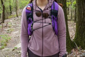 Woman shows fleece jacket laying flat underneath a pack.