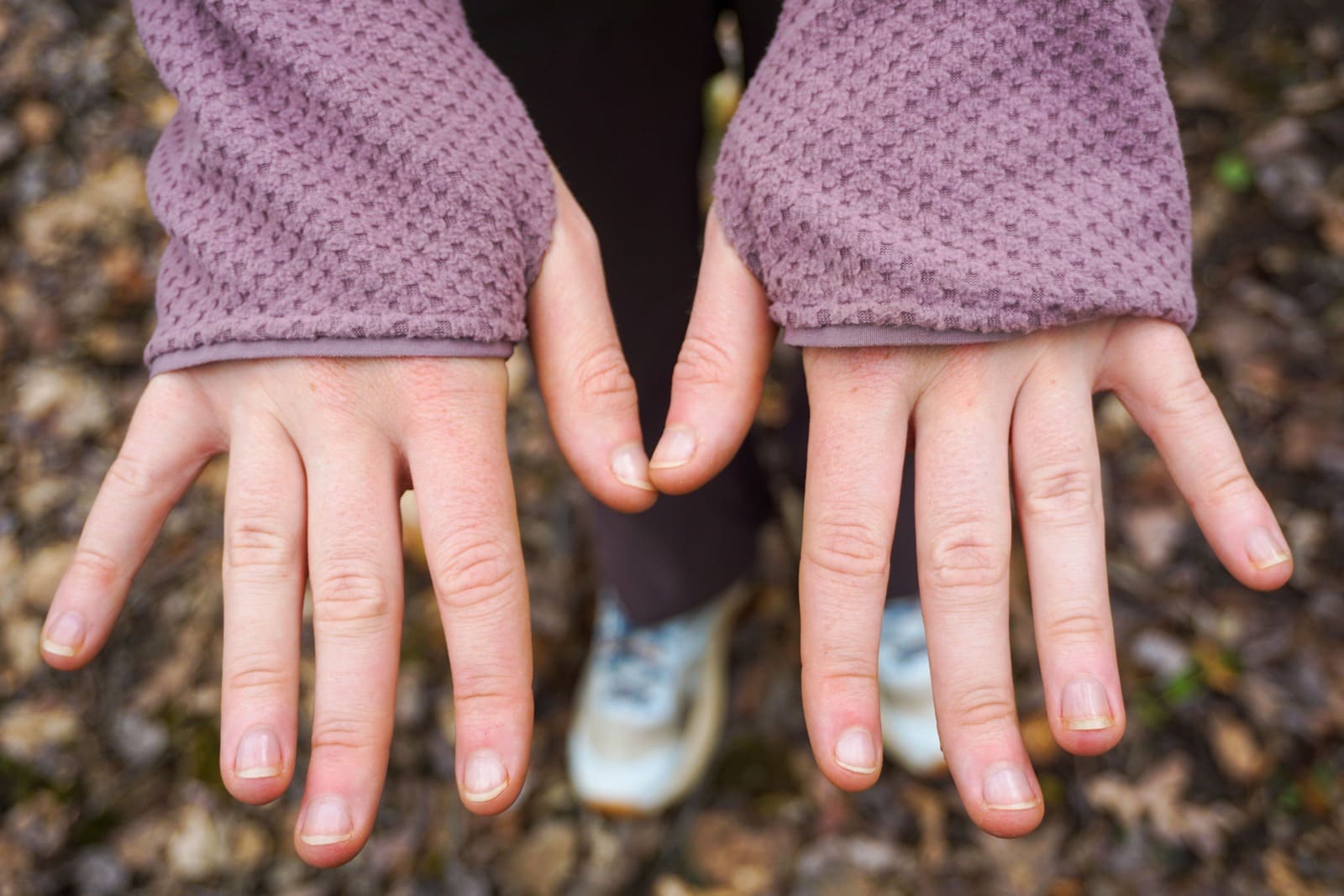 Woman shows back of hands while wearing jacket with integrated thumb holes.