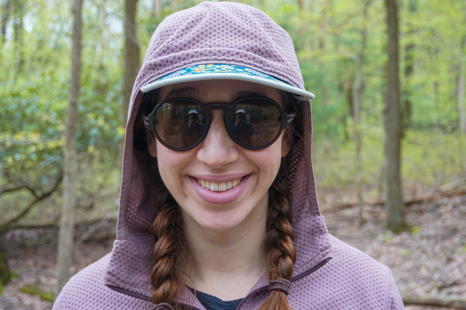 Woman faces camera and smiles with jacket hood up over her head