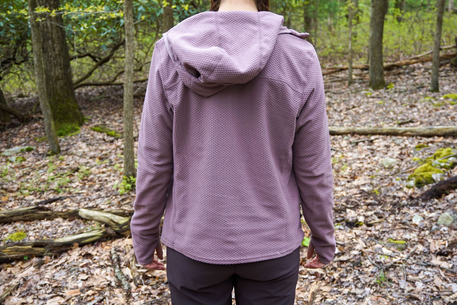 Woman faces away from camera while wearing hoodie to show where the hood falls.