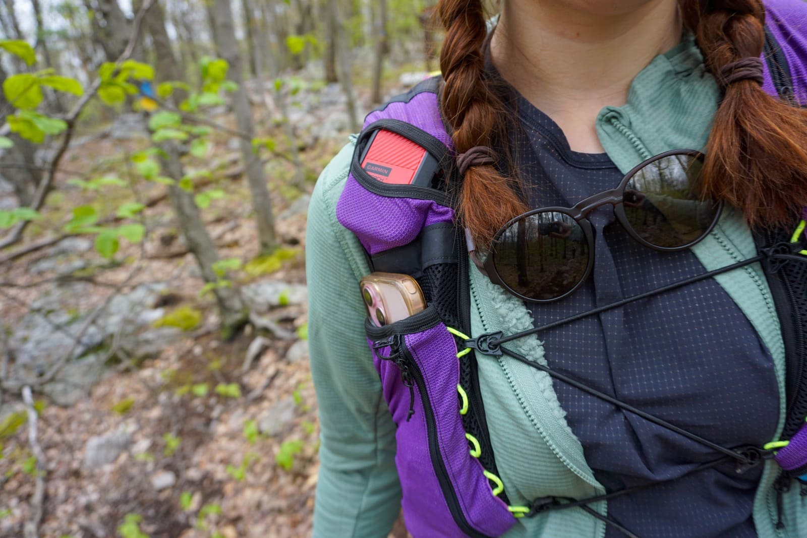 Woman shows fit of green jacket underneath running vest