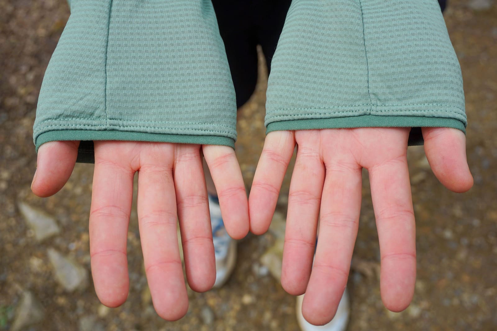 Woman shows palms to camera while wearing a jacket without thumb holes.