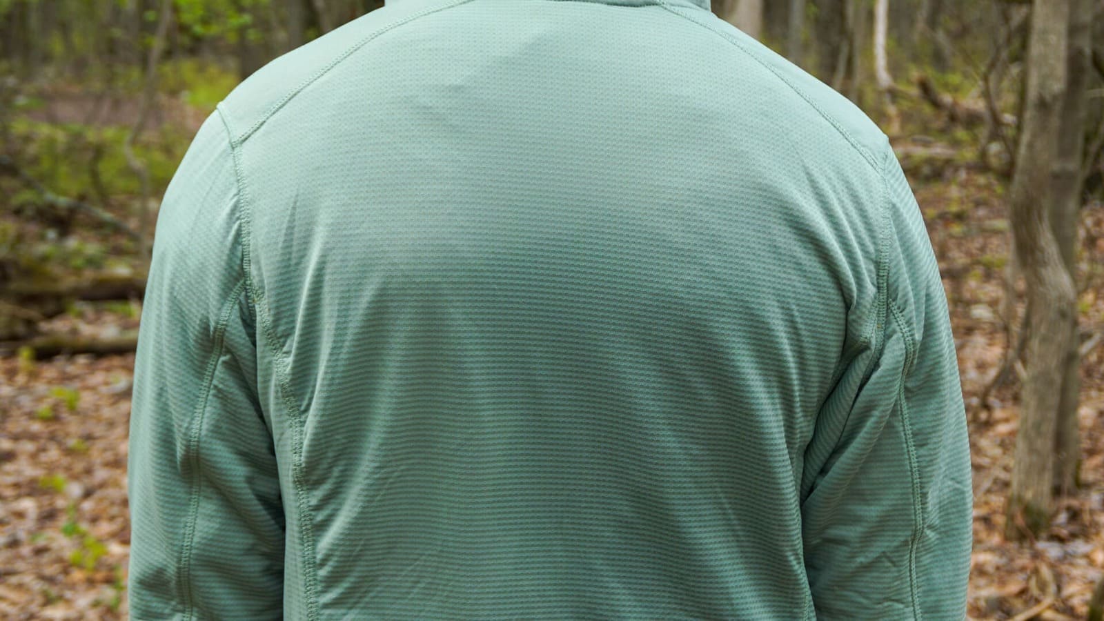 Woman faces away from camera while wearing fleece to show how the shoulder seams naturally fall