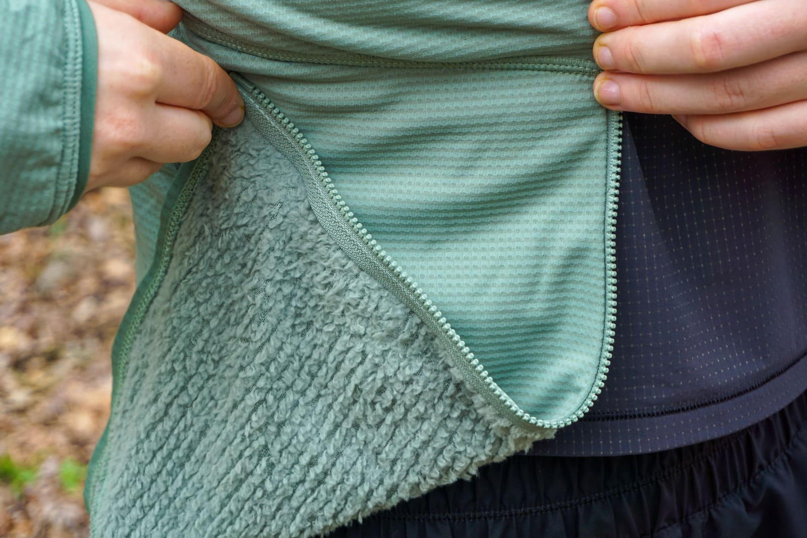 Woman shows contrasting fabric of the inside of the jacket (fuzzy) and the outside (smooth)