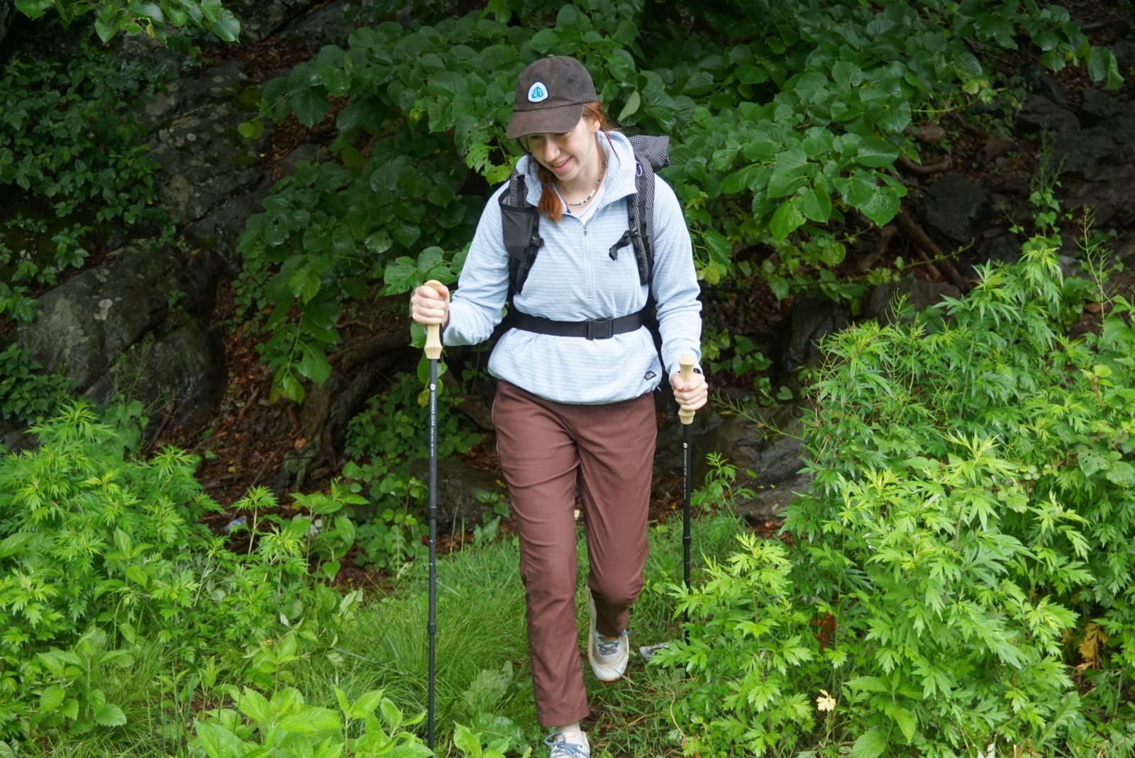 A woman hikes out of the woods.