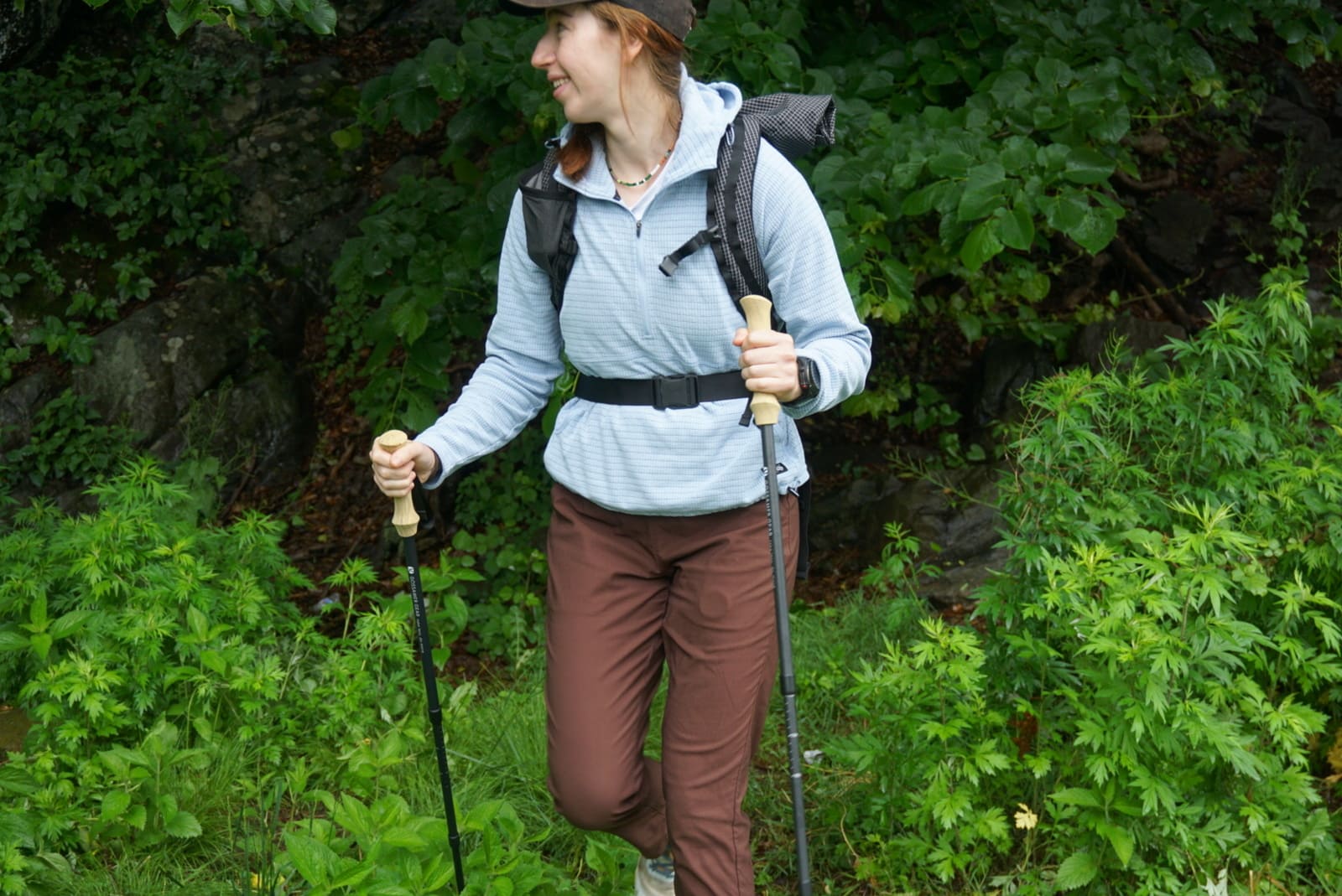 Woman hikes out of woods while looking away from camera