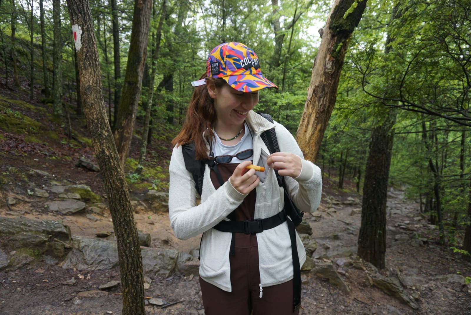 Woman places chapstick inside zippered chest pocket of jacket.