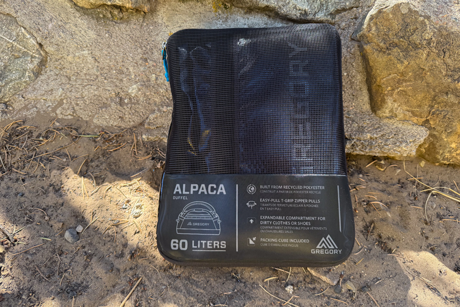 Gregory Alpaca 60 duffel packed inside its included black mesh packing cube with product details visible on the front.