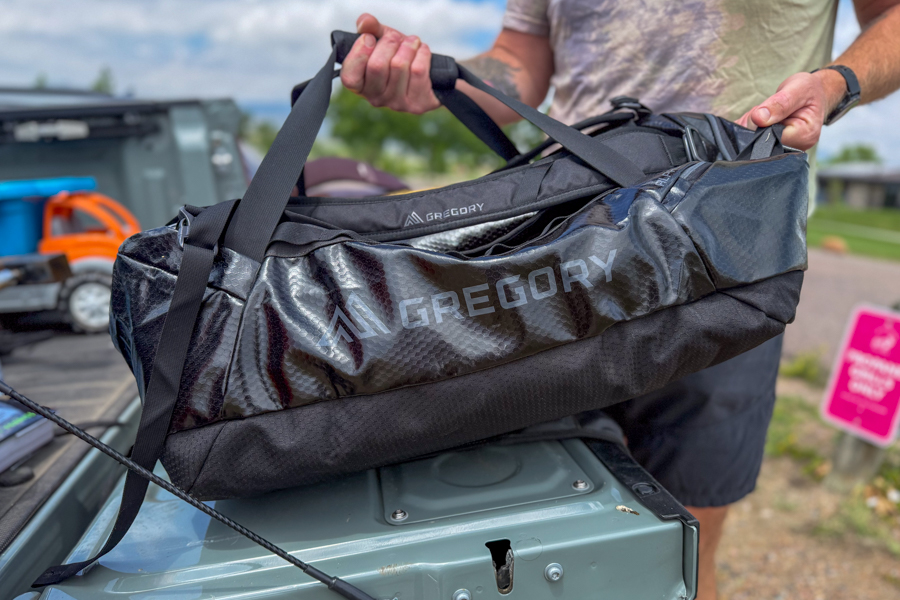 Person lifting the black Gregory Alpaca 60 duffel into the back of a pickup truck.