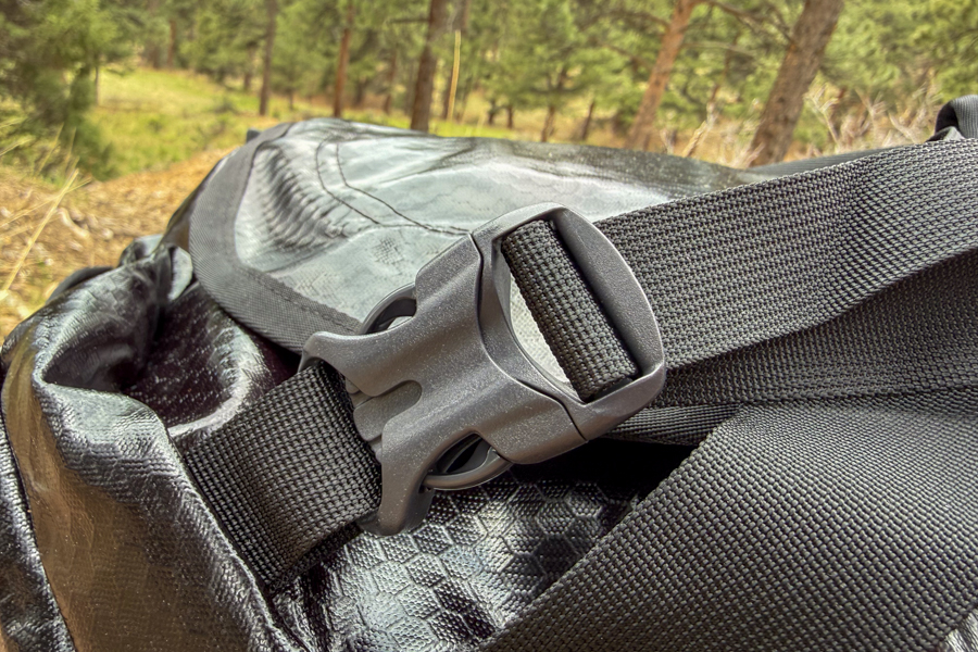 Close-up of the Gregory Alpaca 60 padded shoulder strap attachment hardware on the black duffel.