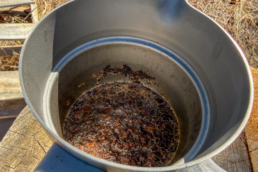 Inside view of a French press showing wet coffee grounds and sediment collected at the bottom after pouring.