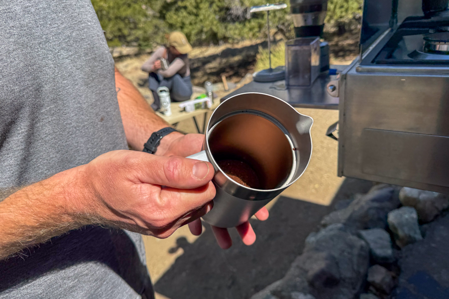 Ground coffee measured into the stainless steel interior of a French press before brewing.