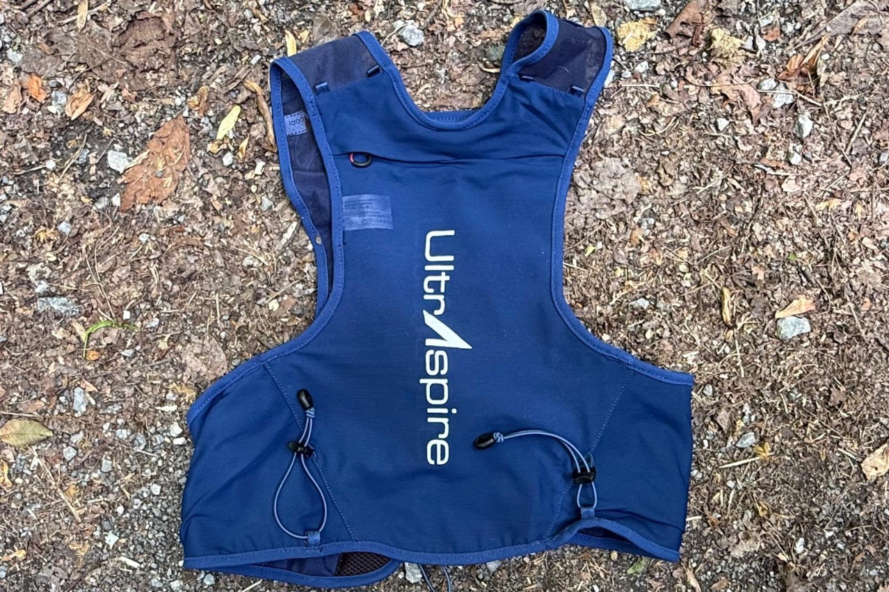 Close-up image of the back of a blue running vest. The vest is lying on rocky ground.