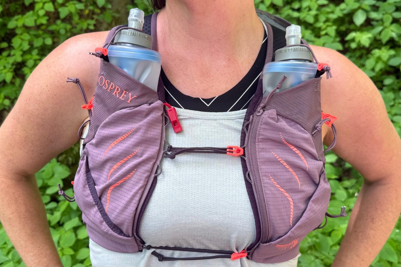 Close-up image of the front of a purple running vest showcasing the sternum strap and two water flasks.
