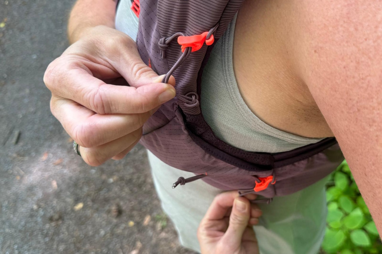 Close-up of the front trekking pole attachments on a purple running vest.
