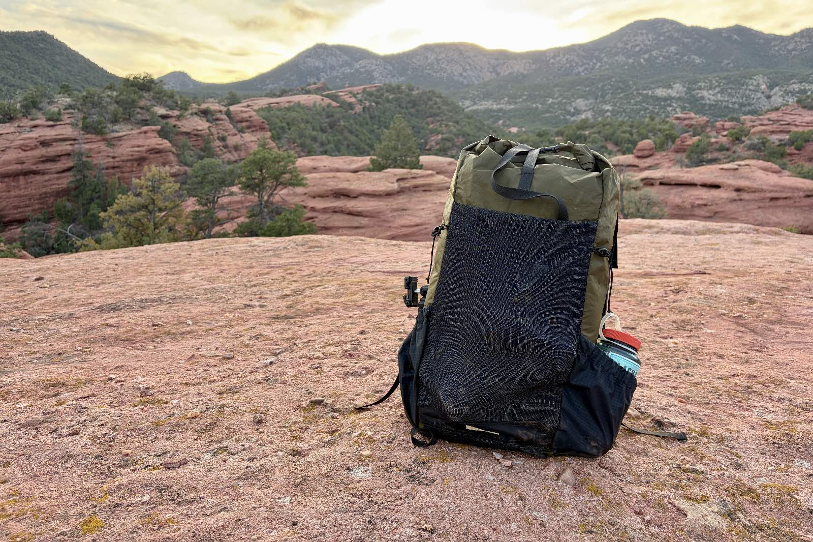 A green backpack sits on red sandstone.