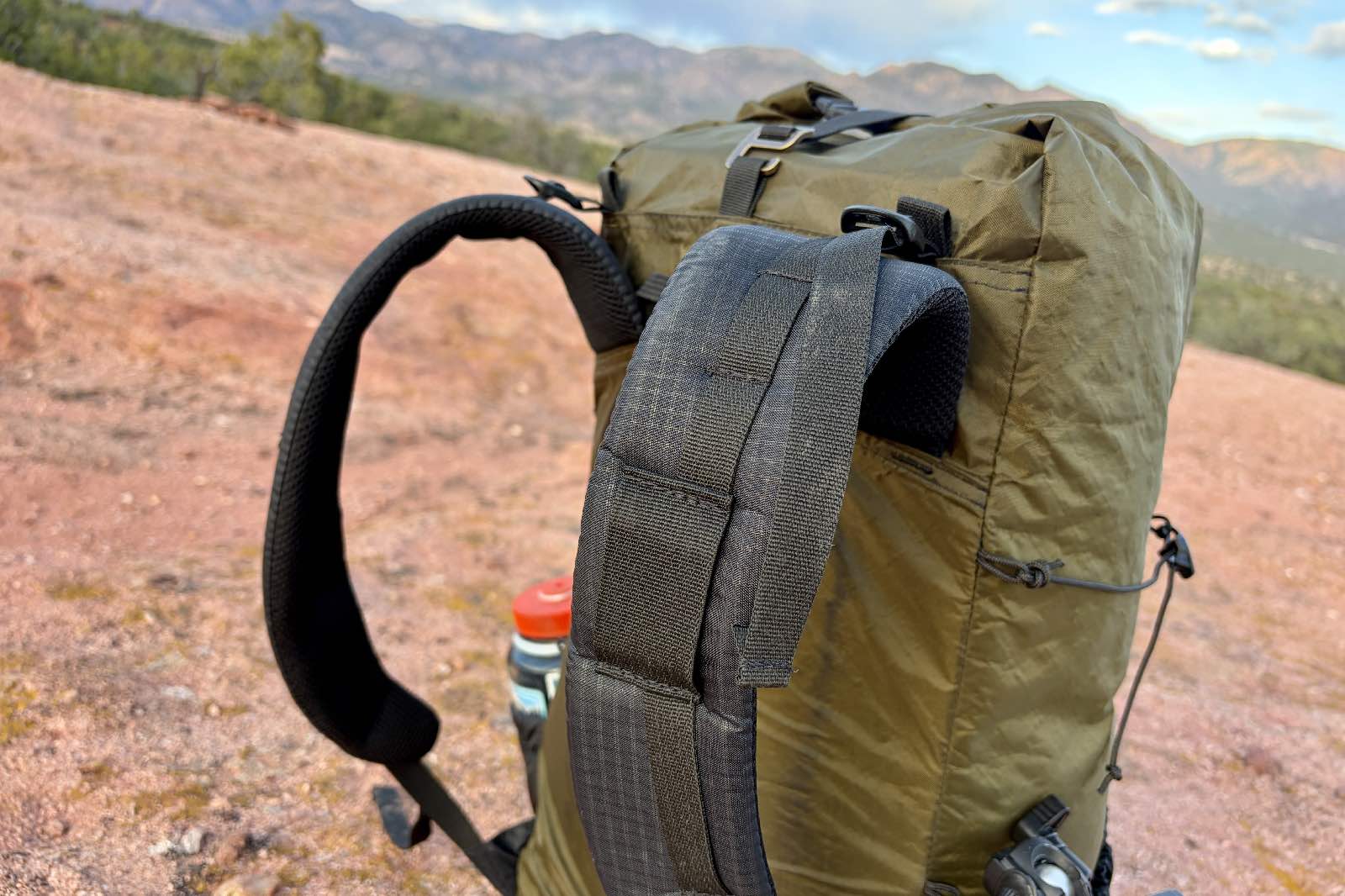 A green backpack sits on red sandstone.