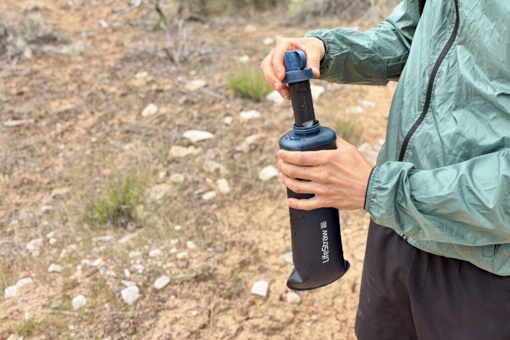 A hiker inserts a water filter into a water bladder.