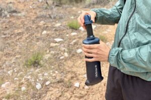 A hiker inserts a water filter into a water bladder.