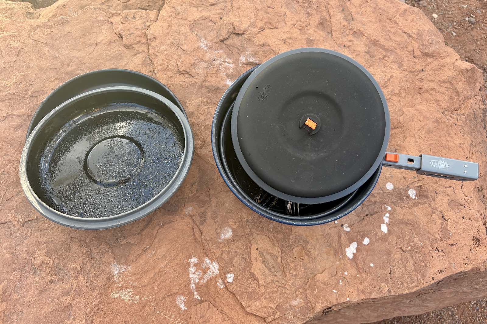 components of a camping cookset on a rock