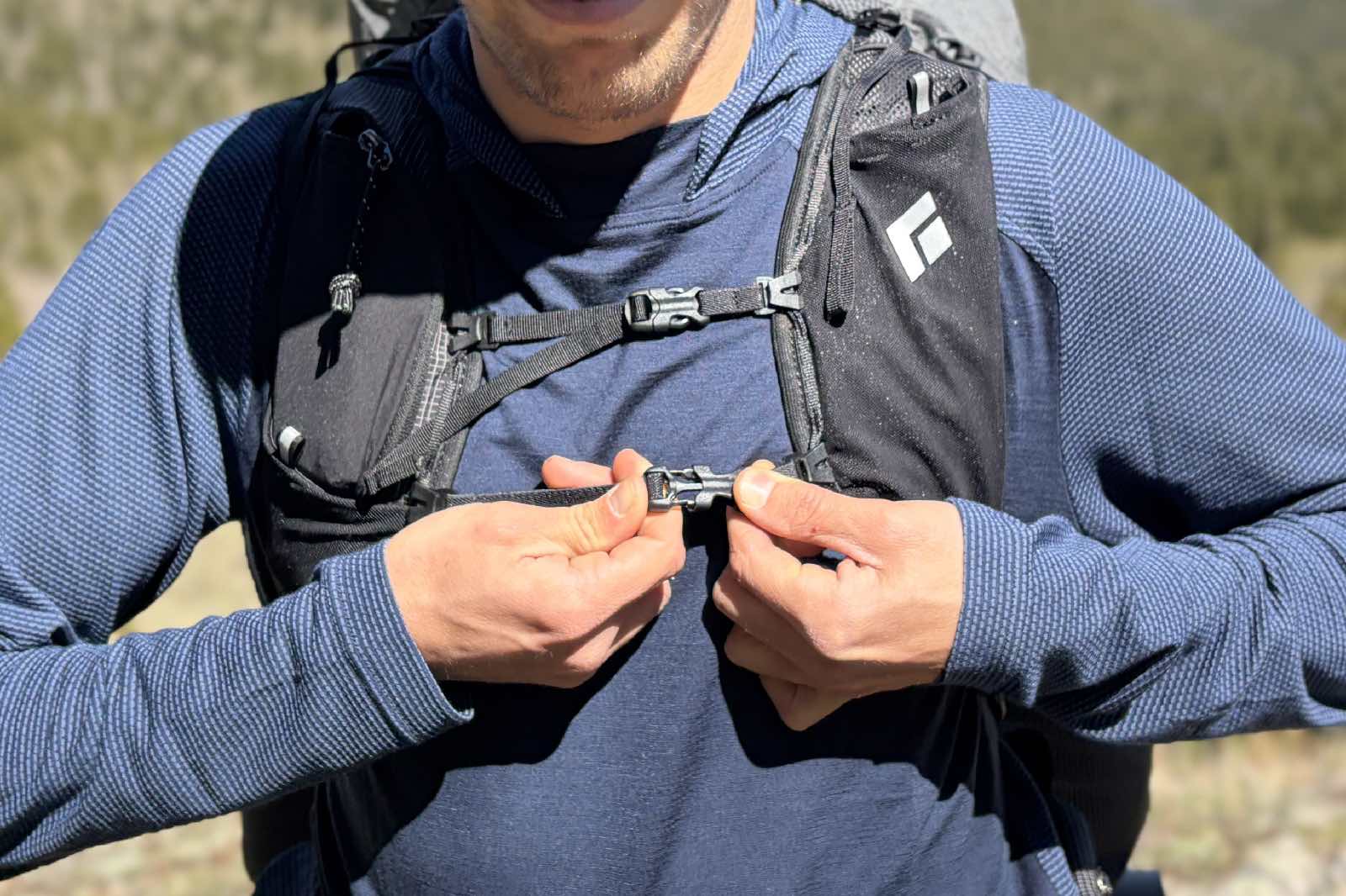 Primer plano de un excursionista cerrando la correa del esternón del arnés de su mochila.