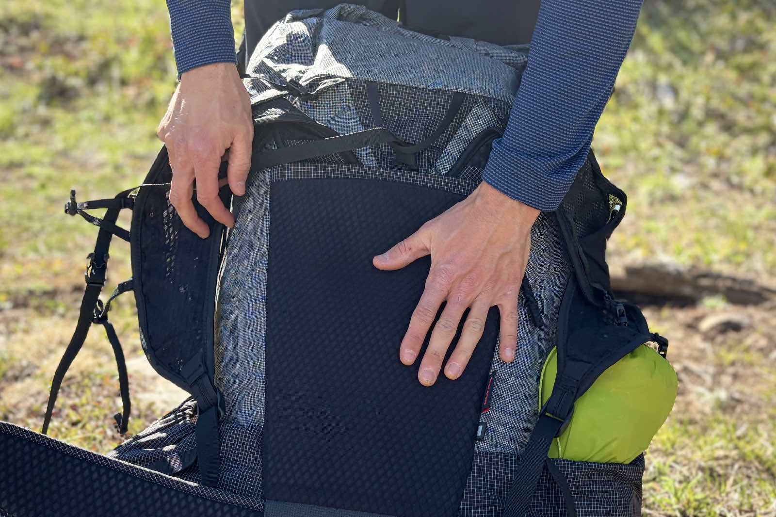 Primer plano de la mano de alguien contra el panel trasero de una mochila.