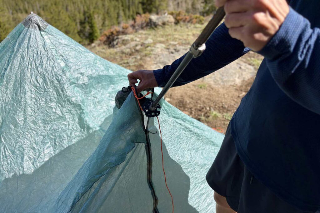 A hiker inserts a trekking pole into a the door of a trekking pole tent