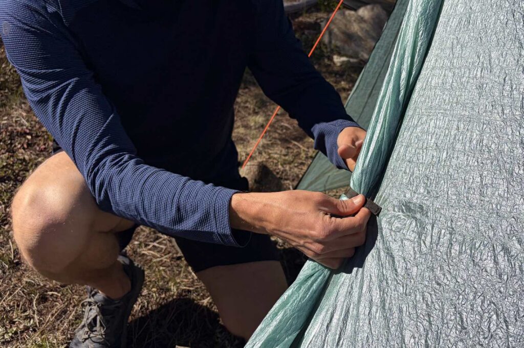 a hiker rolls back the door on a tent