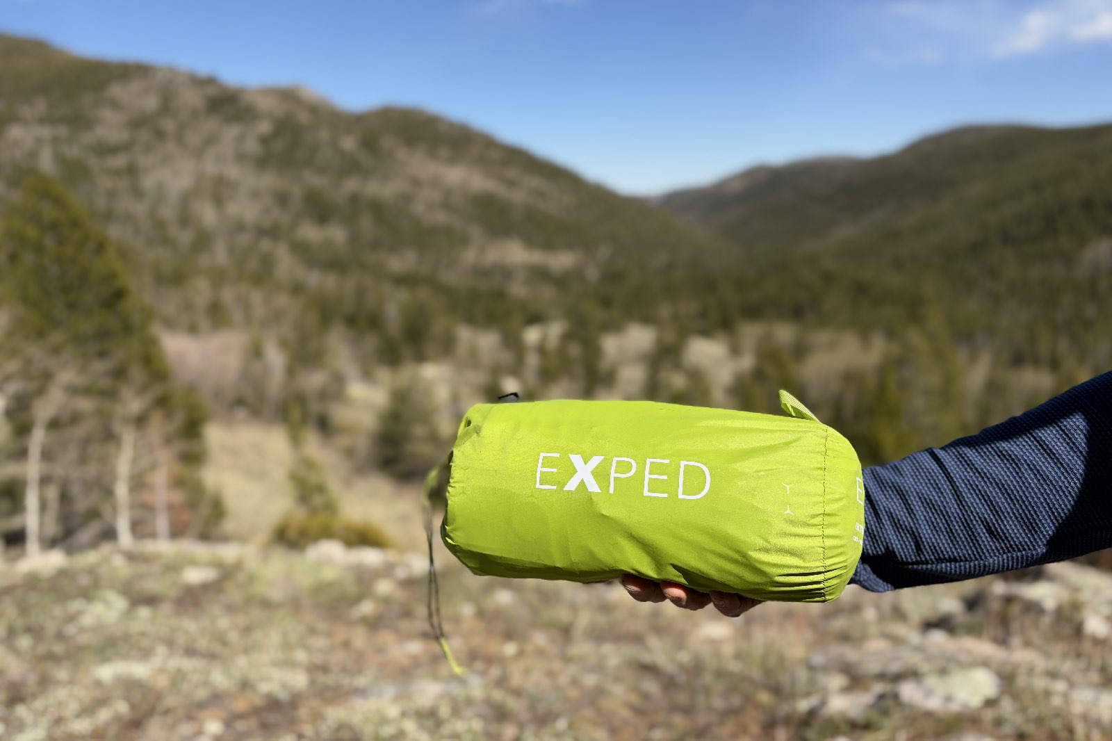 a hiker holds a sleeping pad in one hand