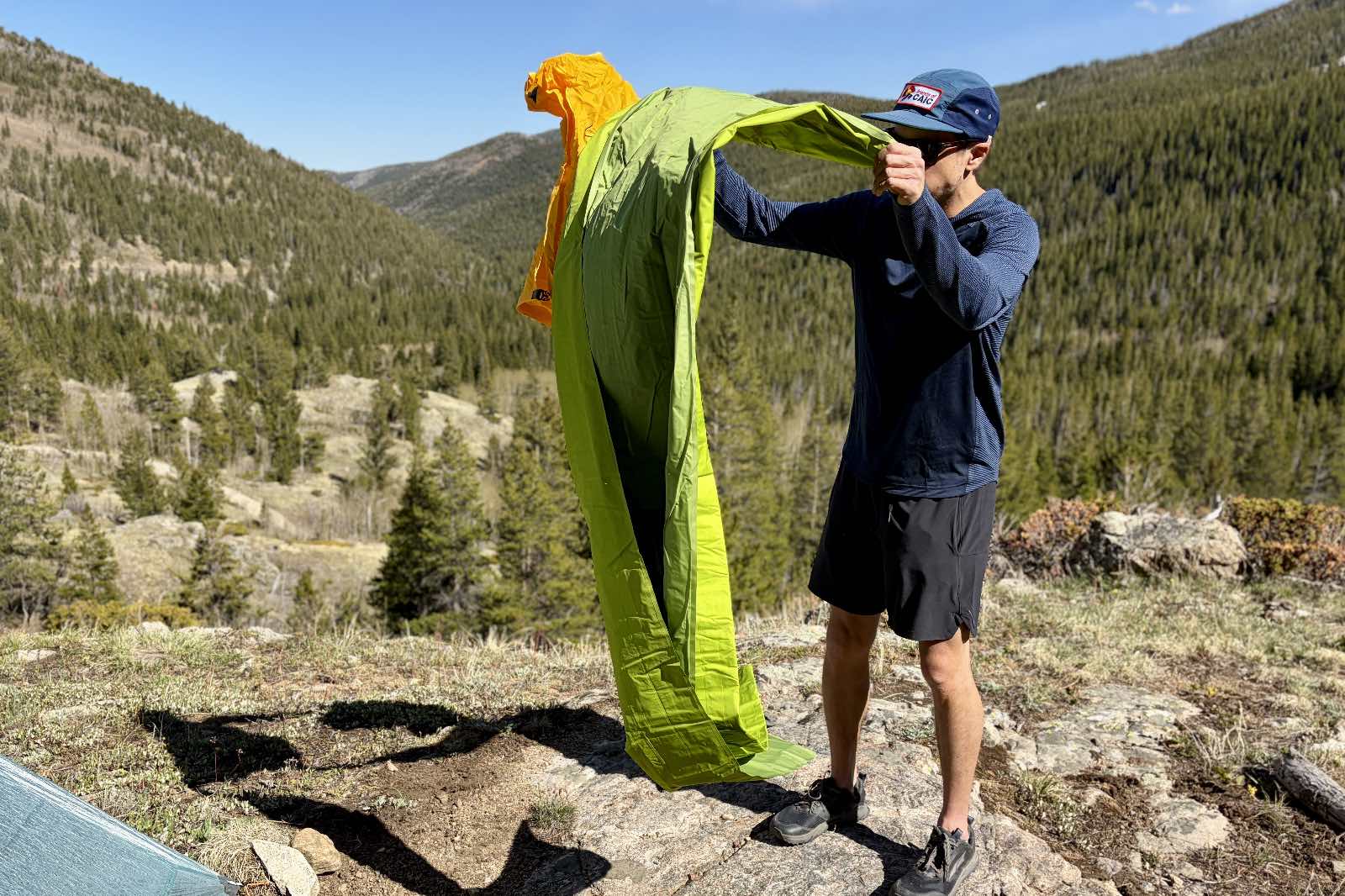a hiker unfolds a green inflatable sleeping pad