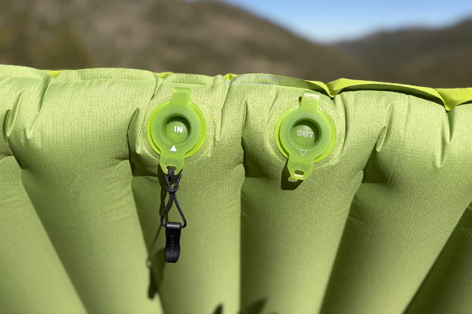 a close up of inflate and deflate valves on a green inflatable sleeping pad