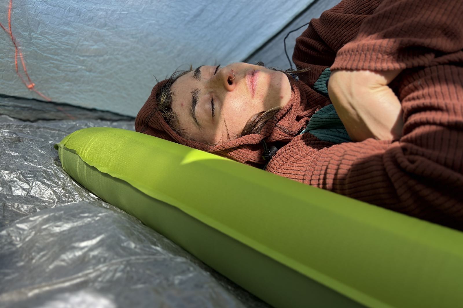 a hiker lays on a green inflatable sleeping pad