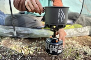 Close-up image of a hiker cooking with a pot and backpacking stove.