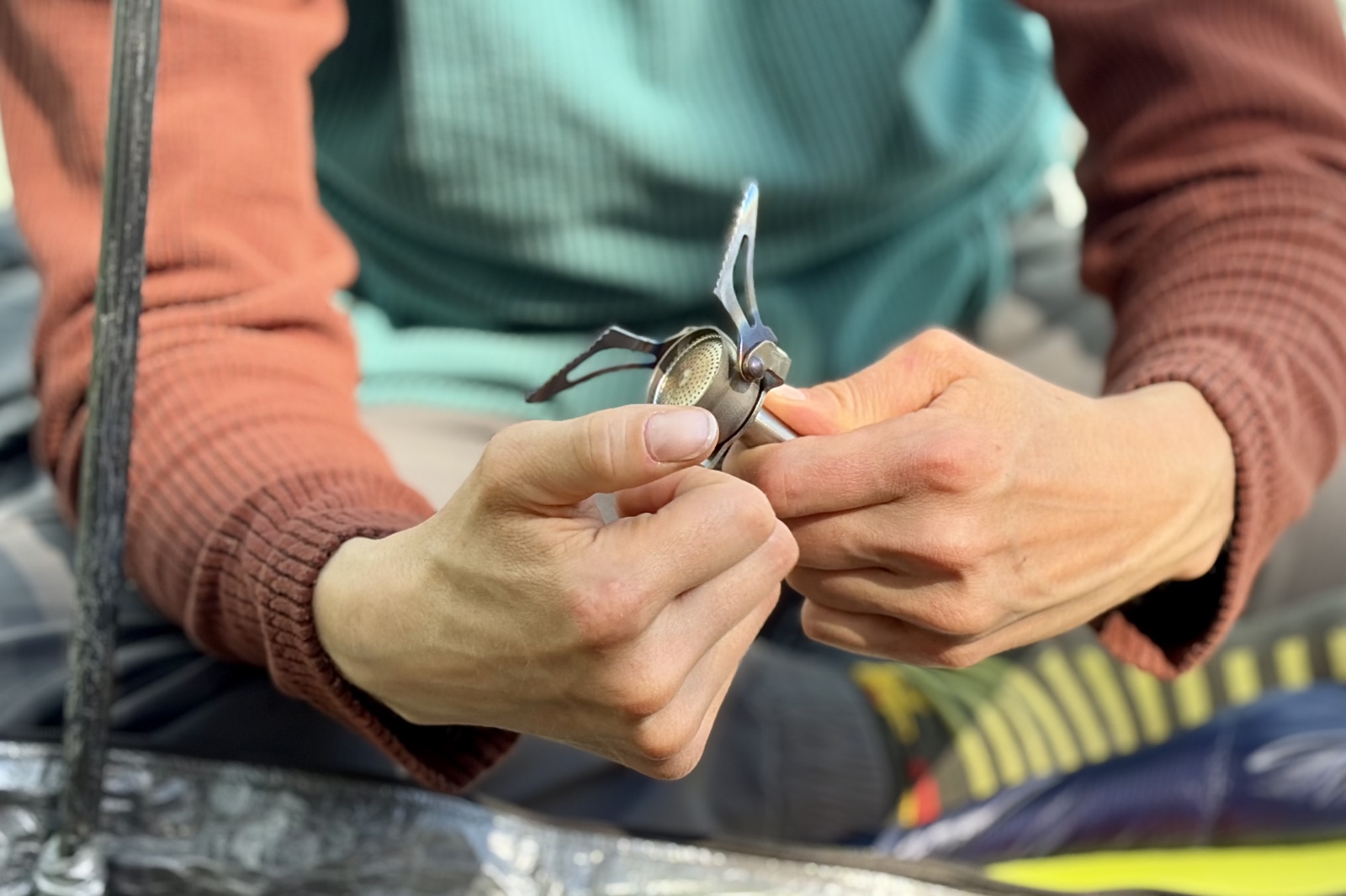 Close-up image of a hiker unfolding a backpacking stove.