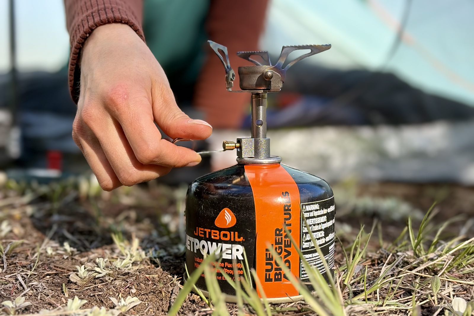 Close-up image of a hand turning the fuel control on a backpacking stove.