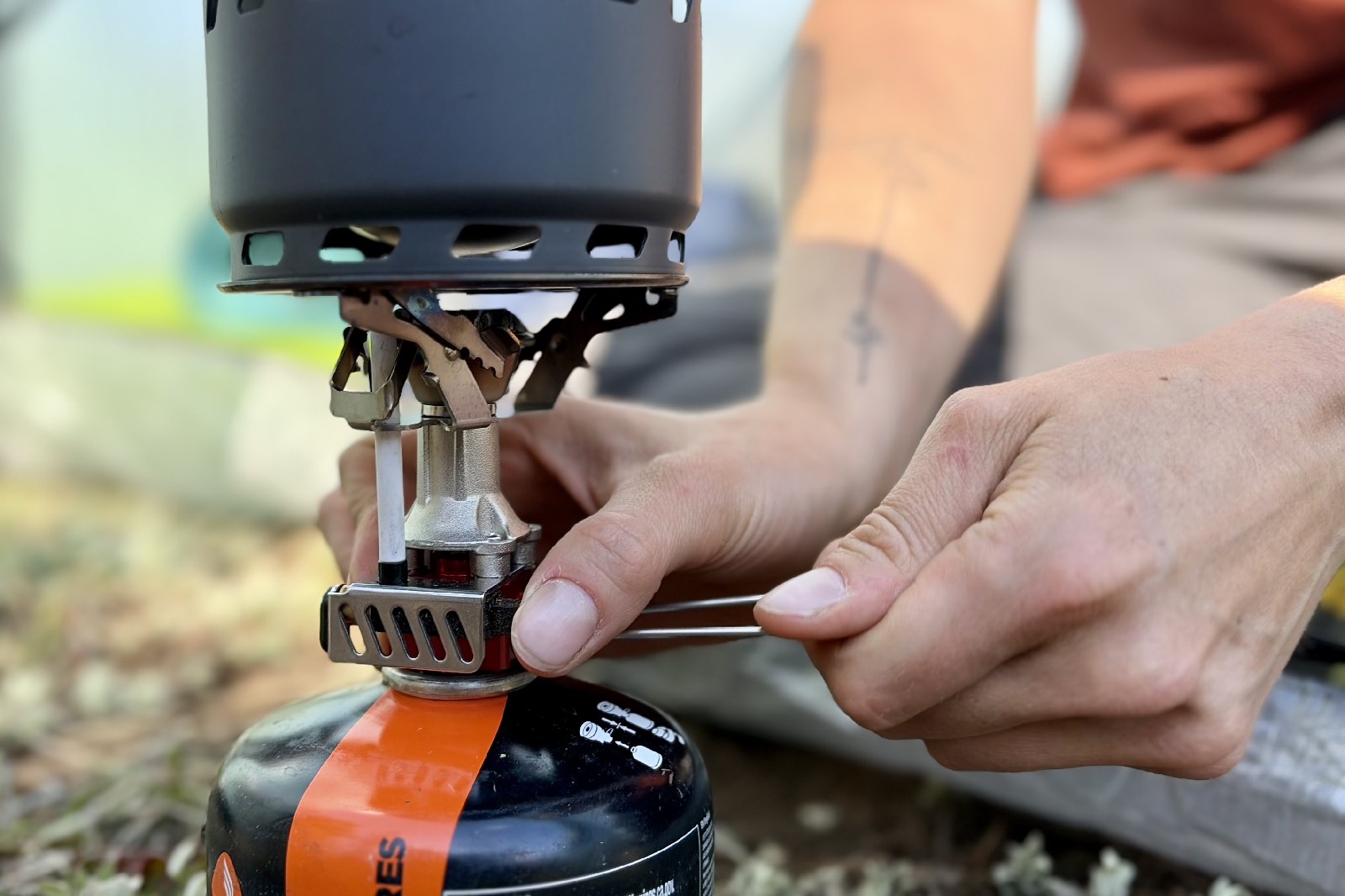 a close up of a hiker pushing the ignition switch on a backpacking stove
