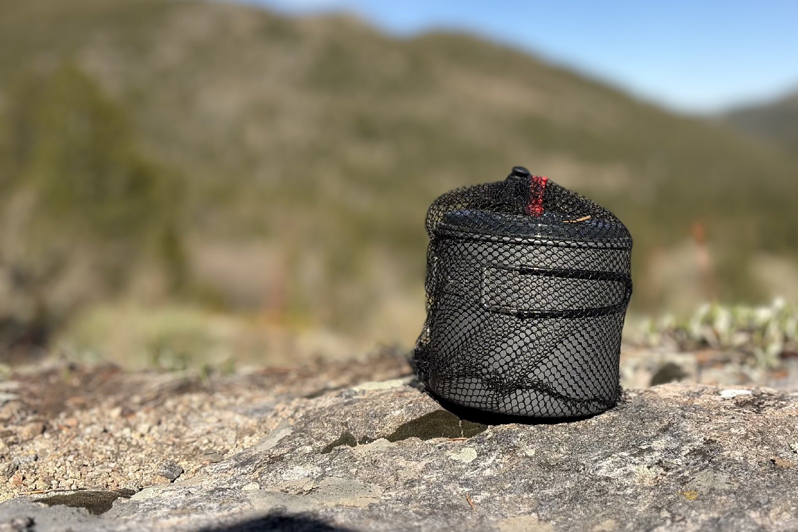 a pot in a mesh bag on a rock