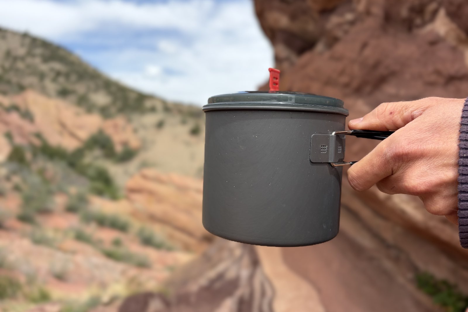 A hand holding a backpacking cook pot
