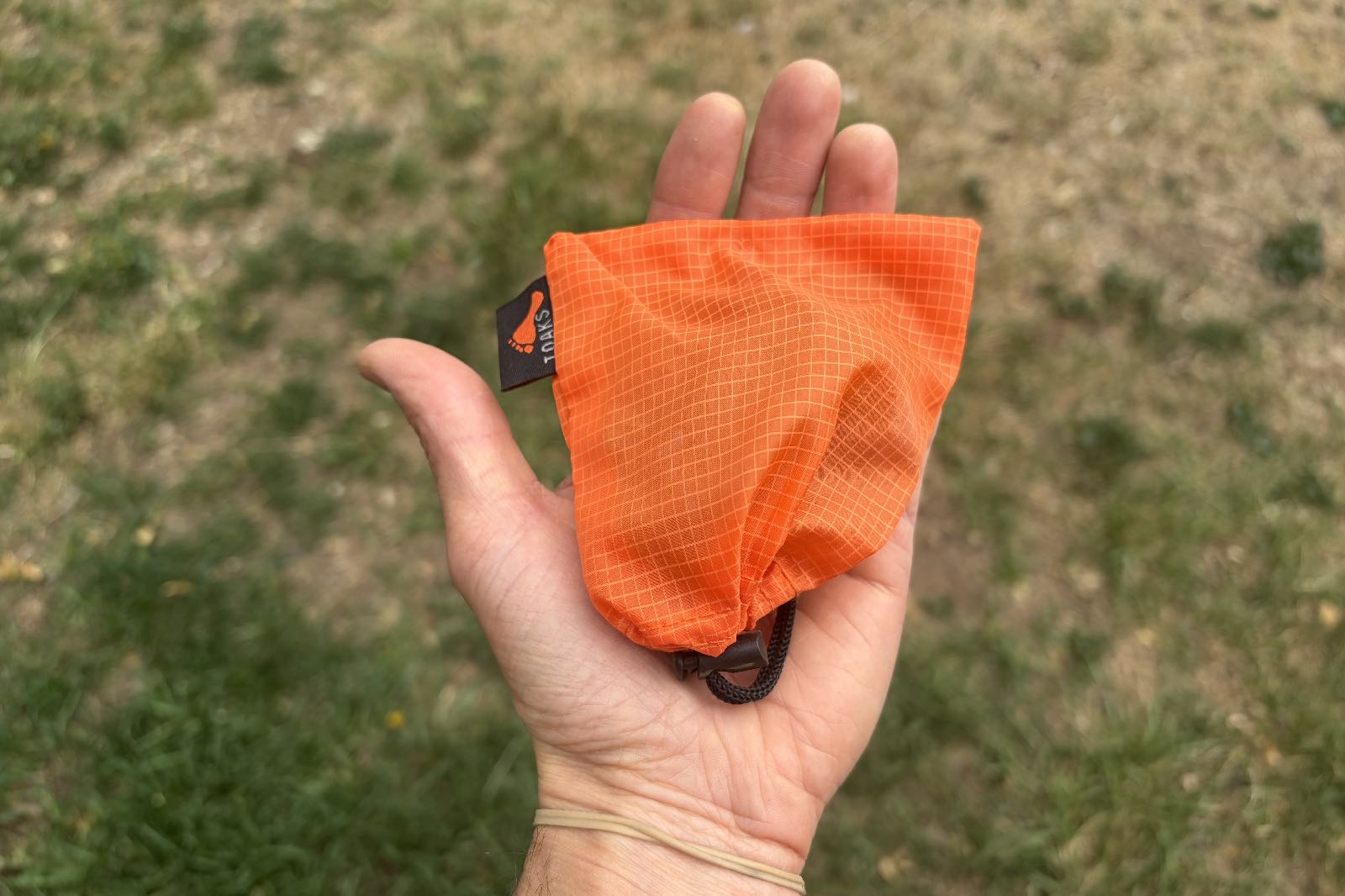 An orange stuff sack in the palm of a hand.