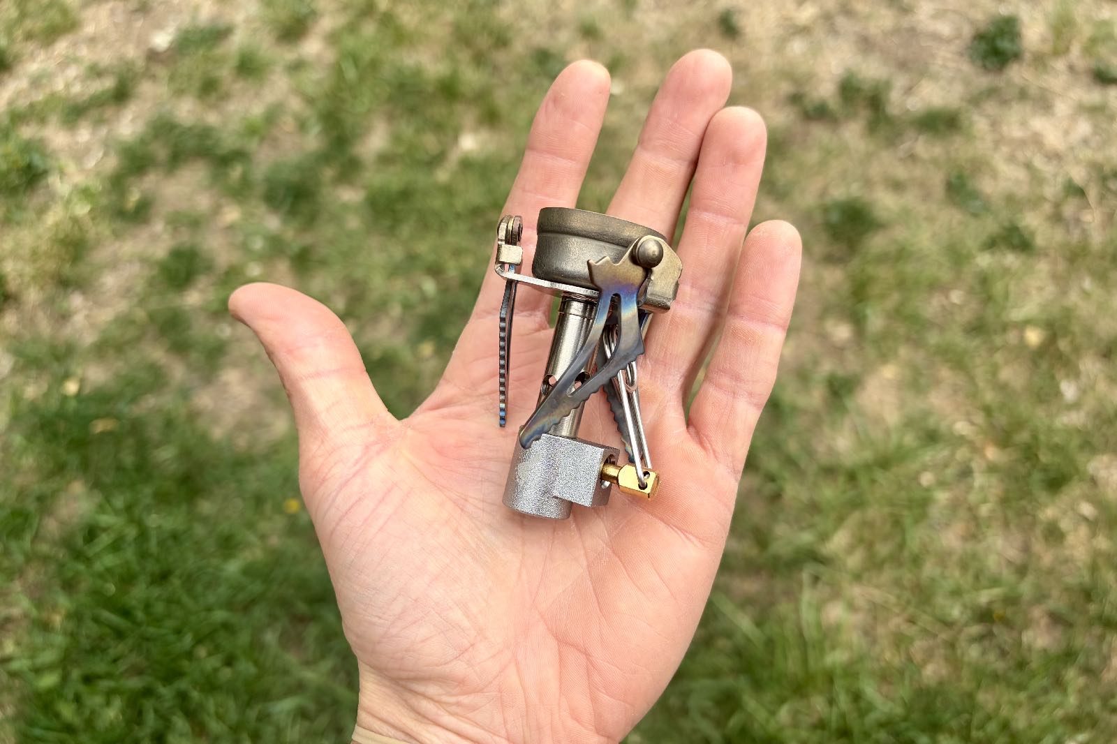 A folded backpacking stove in the palm of a hand.