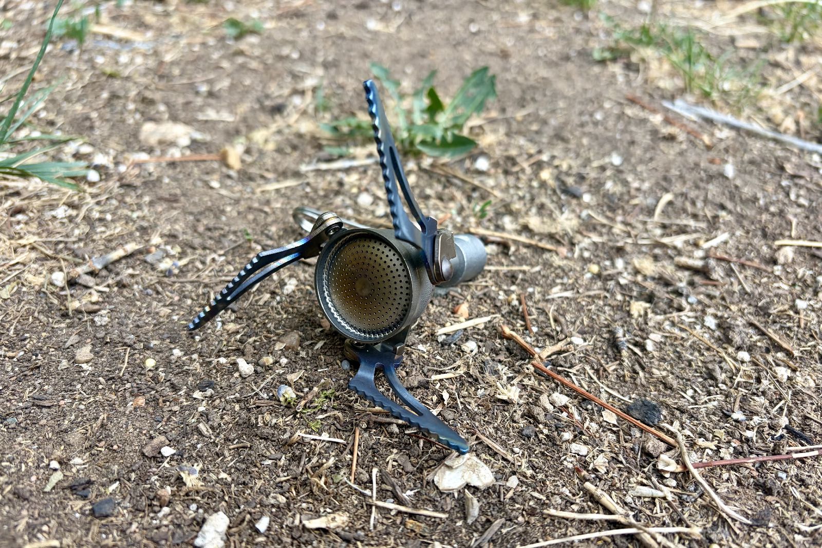 A backpacking stove sitting on the ground.
