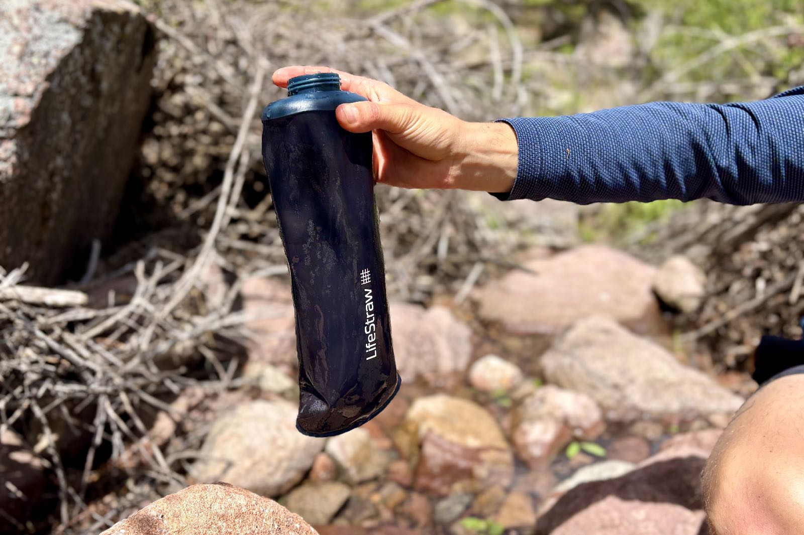 Close-up image of a hiker holding a soft flask water bottle.
