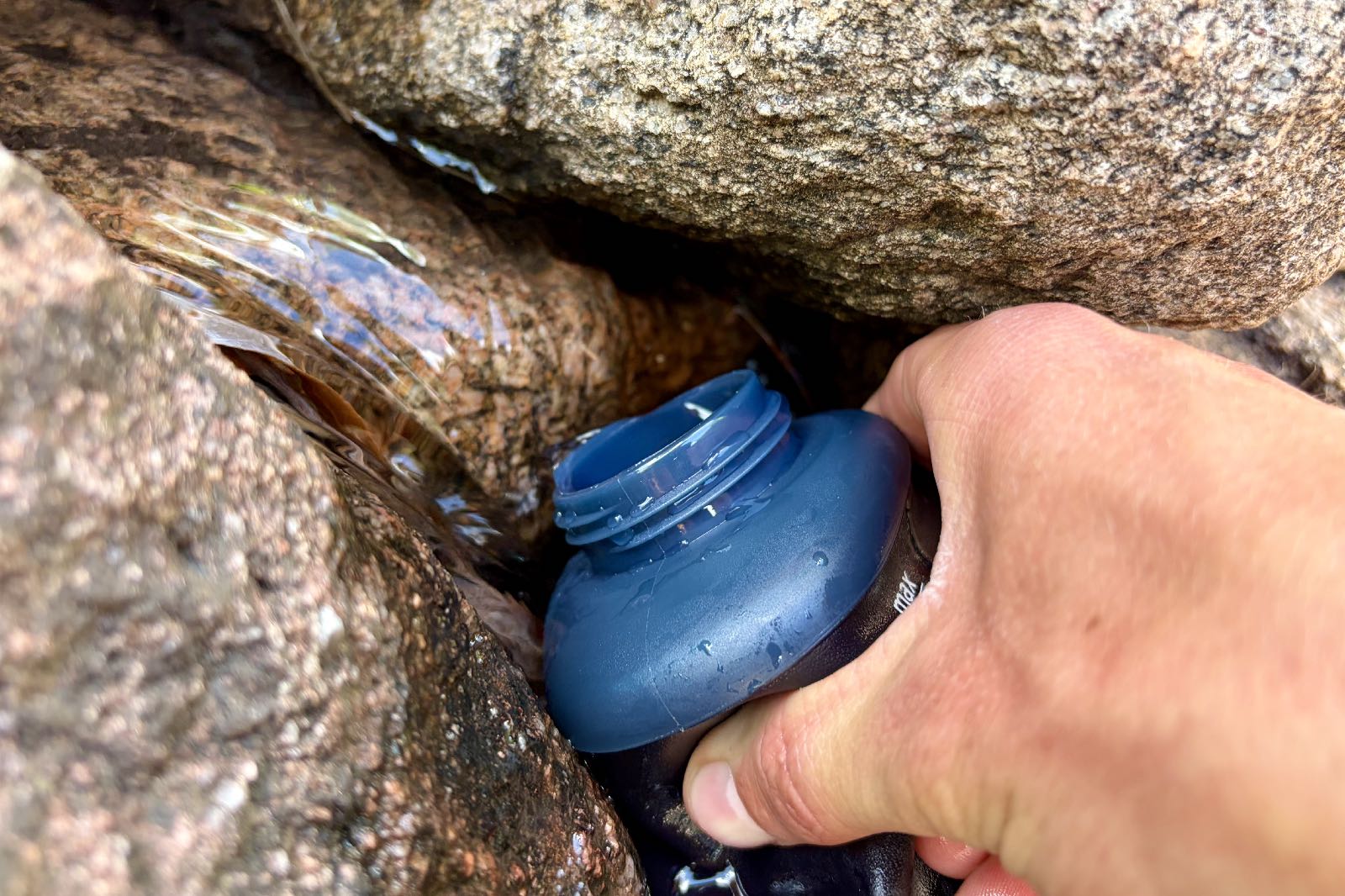 Close-up image of water flowing into a soft flask water bottle.