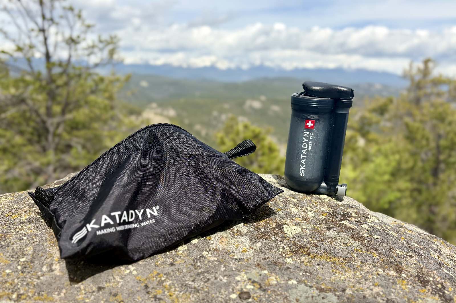 A water filter and storage bag sit on a rock.