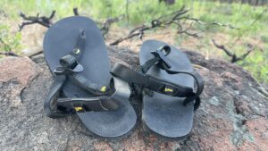 A pair of black sandals sits on a rock.
