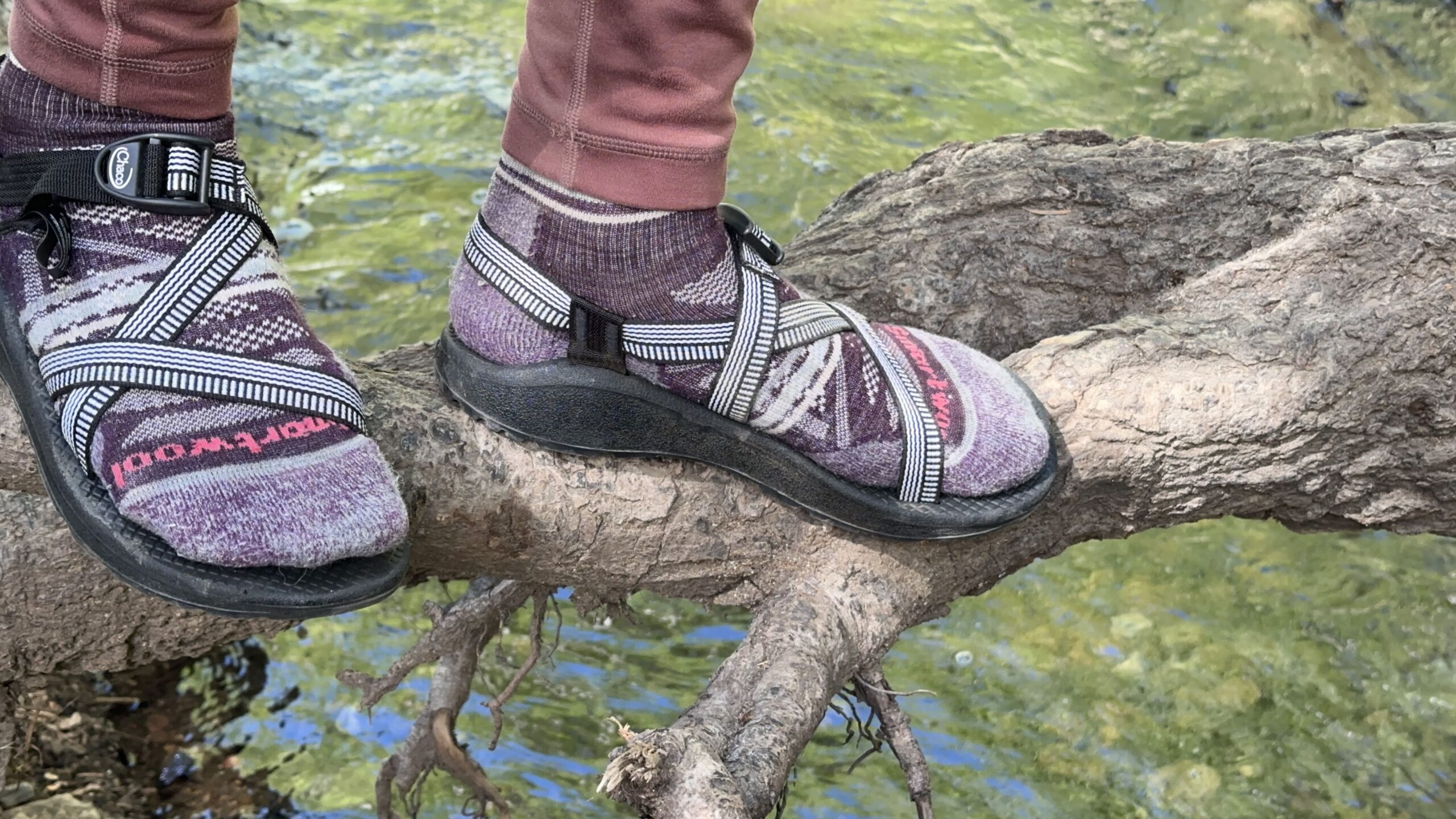A woman walks along a log wearing black sandals.