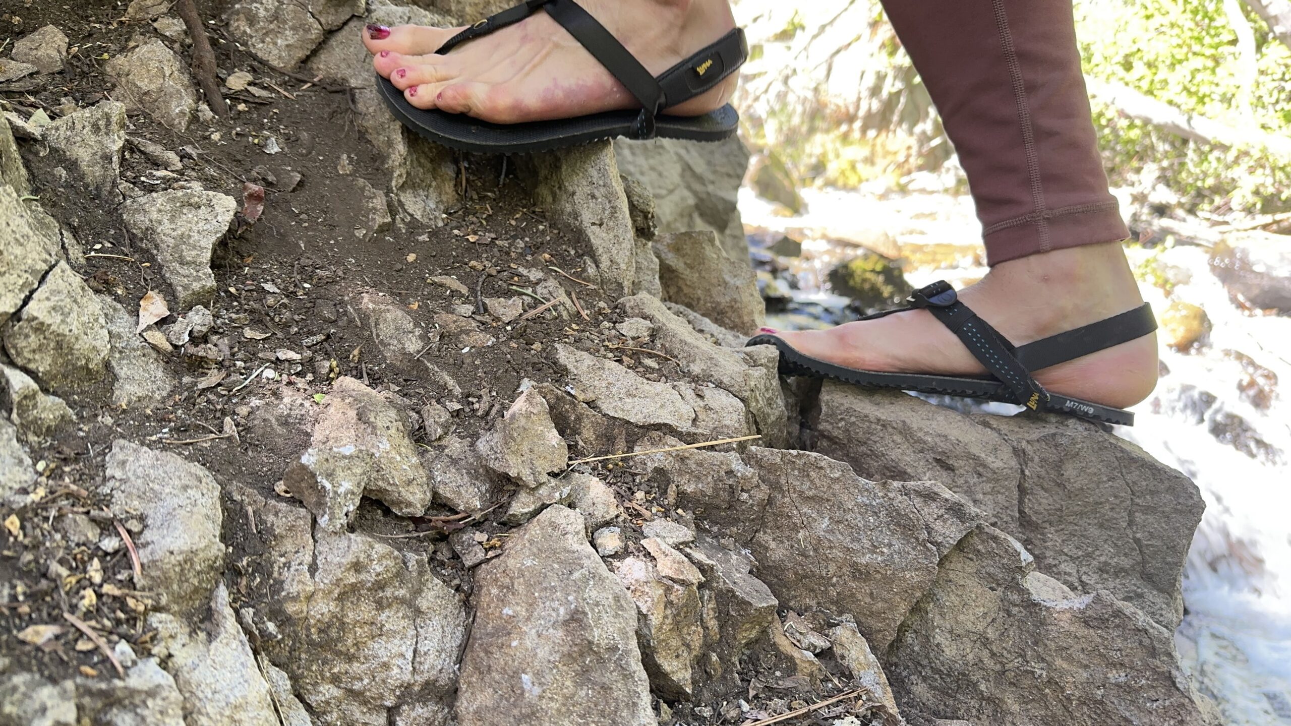A woman walks on rocks.
