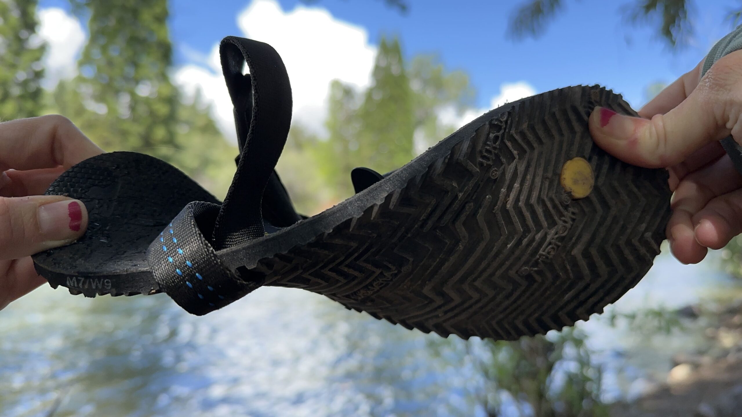 A woman twists a black sandal in front of the camera.